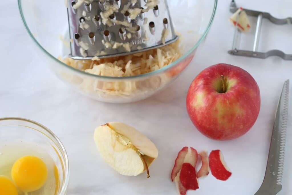 grated apples in a bowl with other muffin ingredients