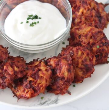 Beet latkes on a plate with sour cream and chive