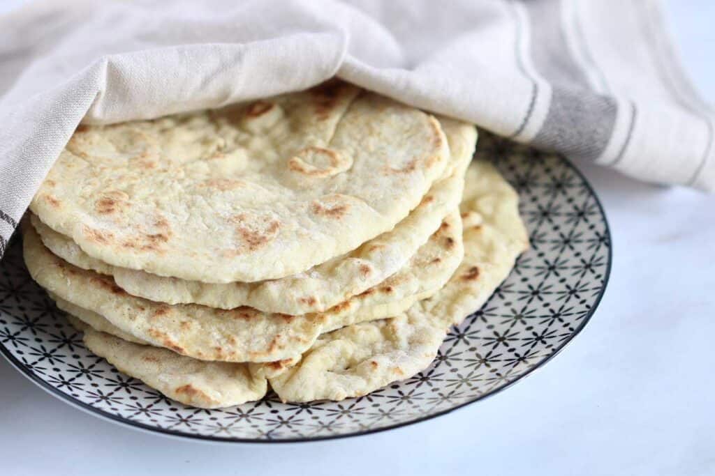 flat bread on a plate covered with a kitchen towel