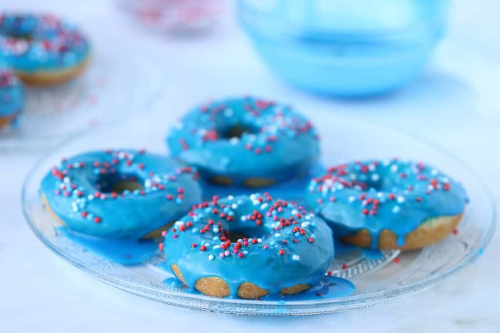 4 baked vanilla donuts glazed with blue glaze on a plate