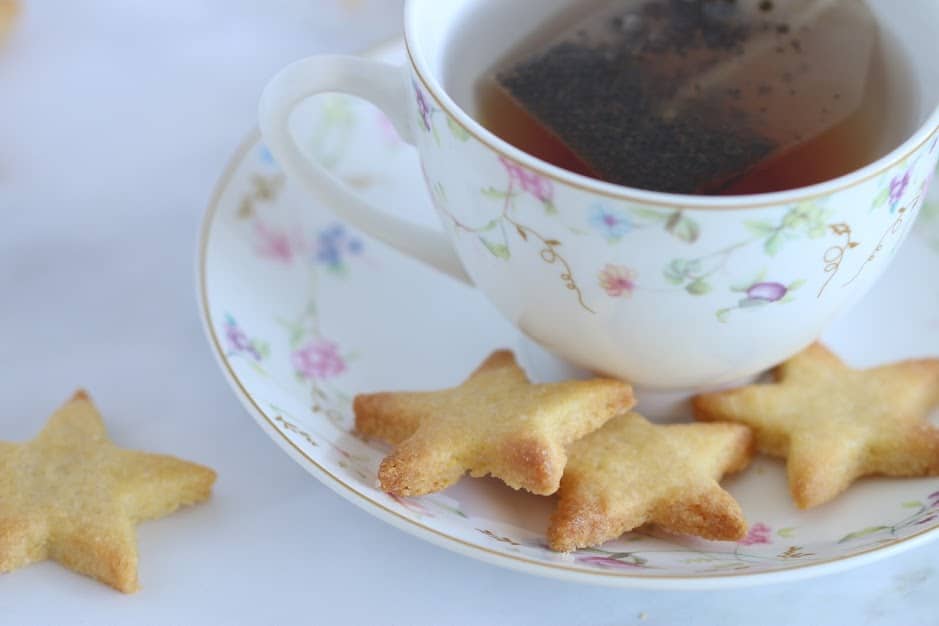 cornmeal cookies on a small plate with a cup of tea