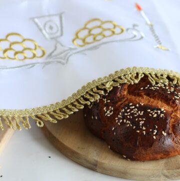 whole wheet challah breads covered with linen