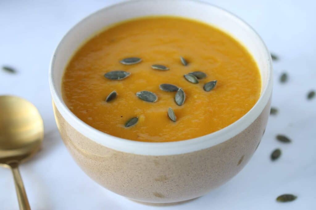 Carrot pumpkin and sweet potato soup garnished with pumpkin seeds