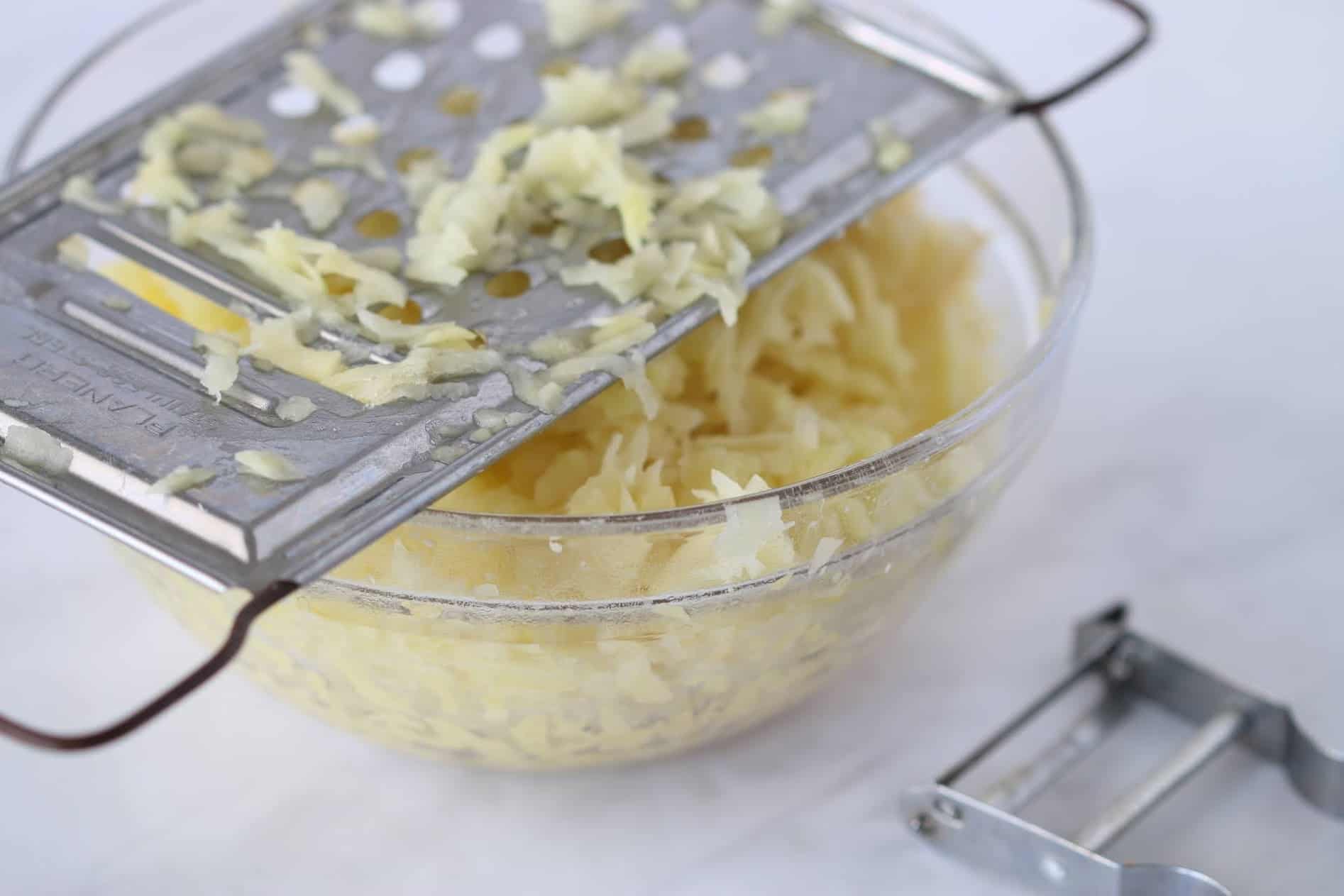 grated potatoes in a bowl and a grater
