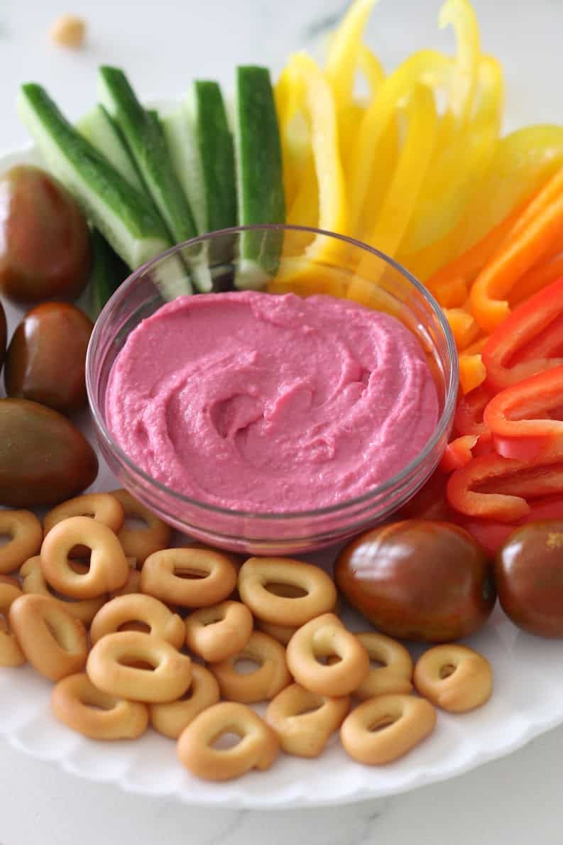 beet hummus served in a bowl with dippers 