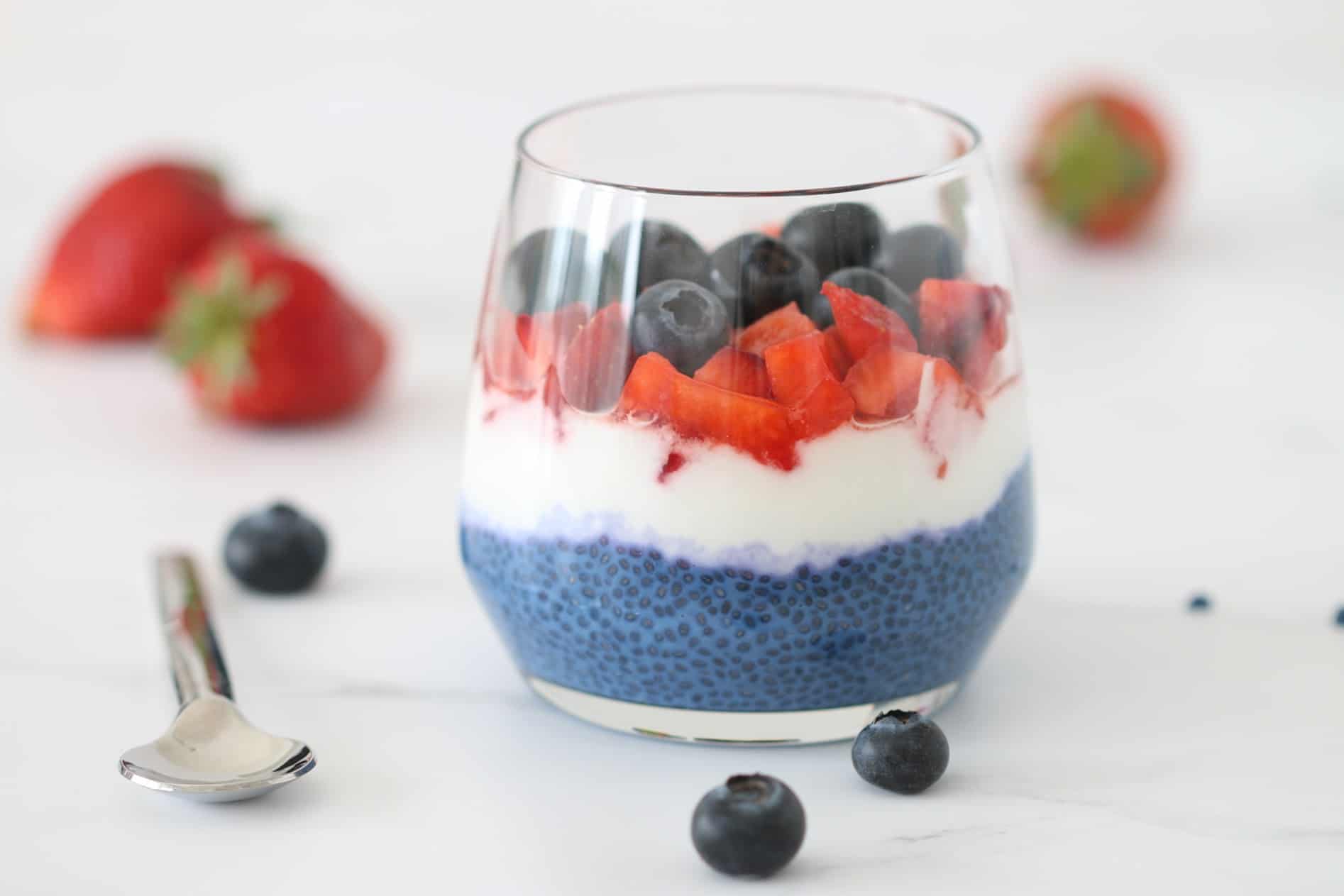 layered blue chia pudding in a cup with Greek yogurt and berries